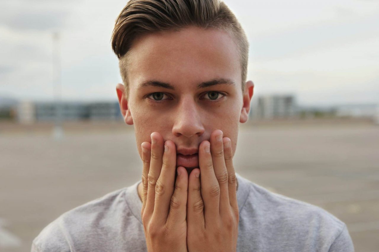 Young man putting his hands next to his mouth