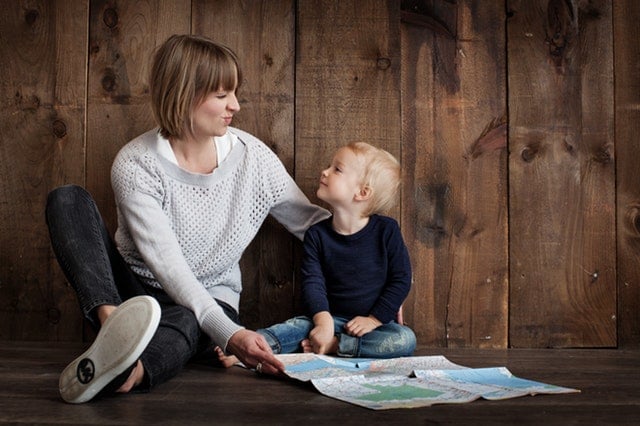 Child sitting on the floor looking up at his mom