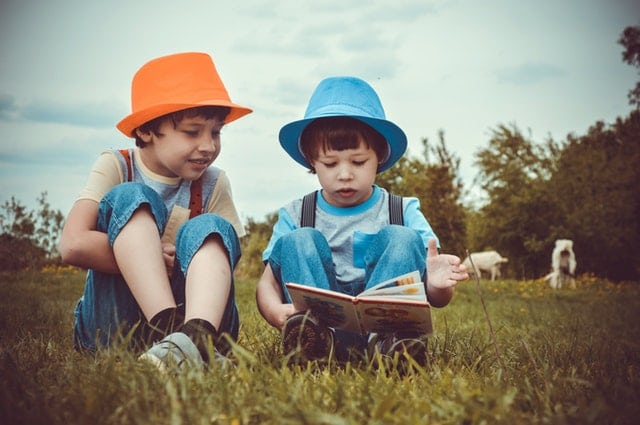 kids reading a book in a field