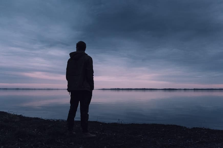 Silhouette of a man standing at a beach near dusk.