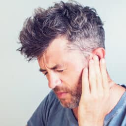 Man with tinnitus holding his ear.