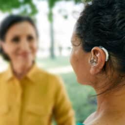 Woman with a hearing aid talking to a friend in a park