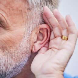 Man cups hand to ear to hear