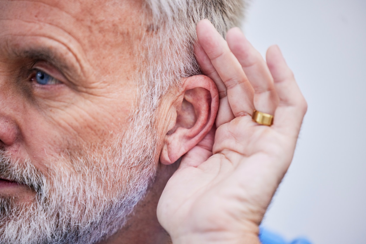 Man cups hand to ear to hear