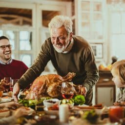 Senior man bringing the thanksgiving turkey to the dinner table