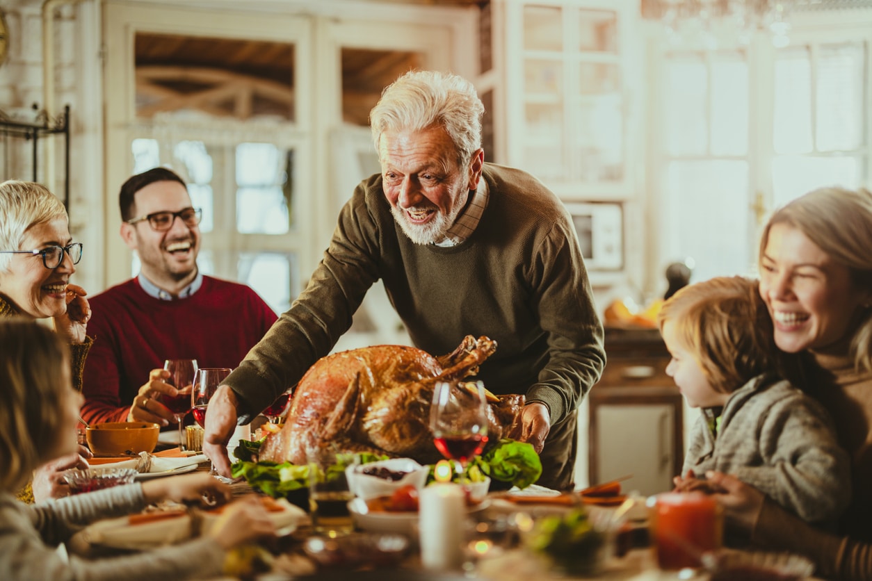 Senior man bringing the thanksgiving turkey to the dinner table.