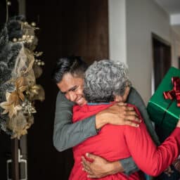 Man hugging a woman after giving her a holiday gift.